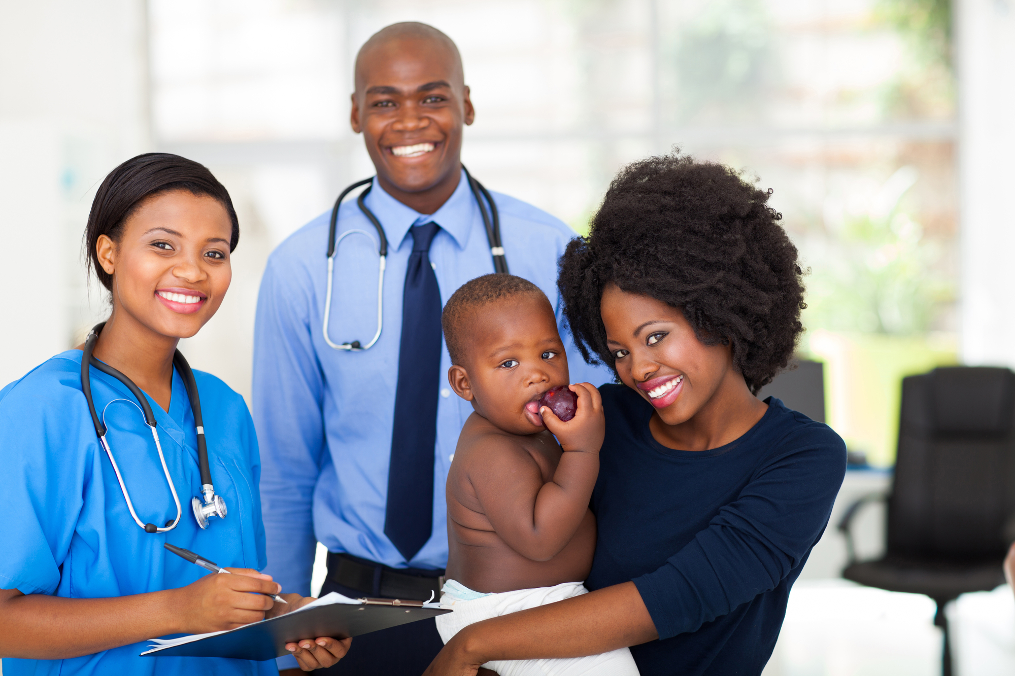 mother holding her baby after checkup with nurse and doctor